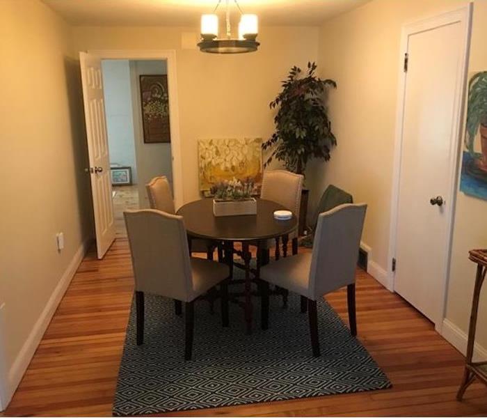 Clean room with hardwood floor table and beige walls