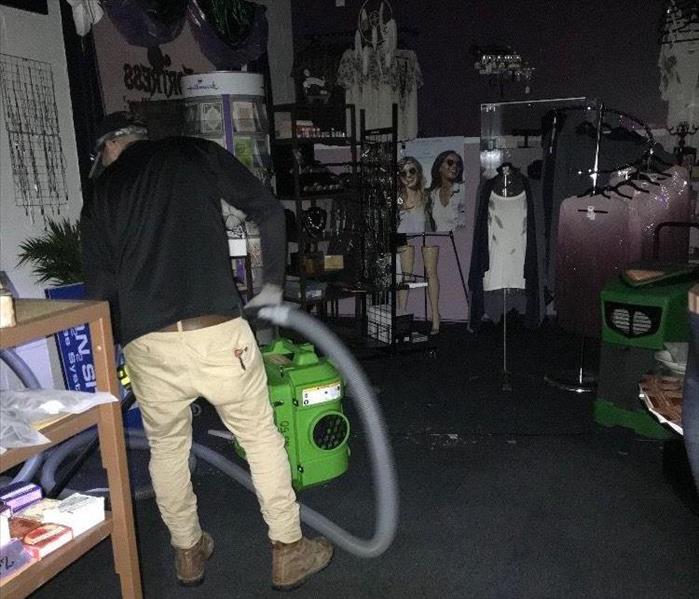 SERVPRO technician in retail store with water extraction equipment 