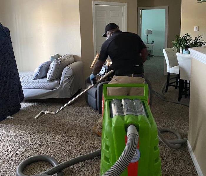 SERVPRO technician with extraction equipment in living room